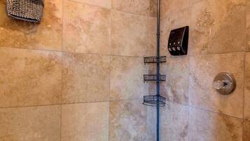 A corner shower with beige tiles, a metal showerhead, and a handheld shower attachment.