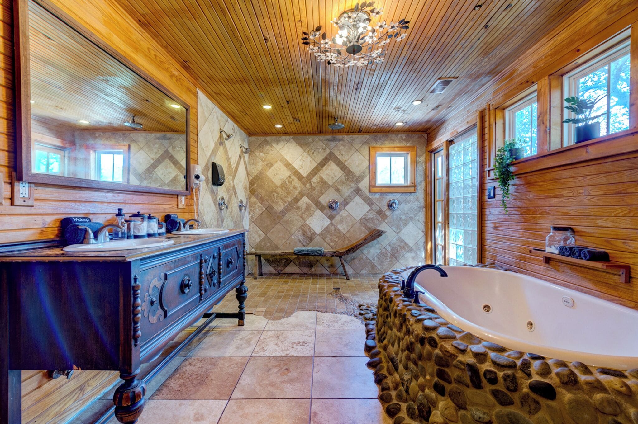A bathroom with a stone tub, wooden vanity, and a large mirror.