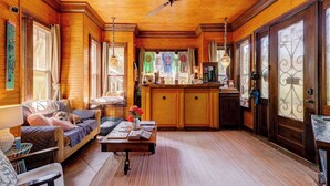 A cozy wooden interior with a sofa, coffee table, and a kitchen area with a bar. - Beachside Boutique Inn – Folly Beach Rooms & Private Cottages (Folly Beach)