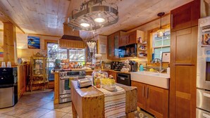 A wooden cabin kitchen with a central island, wooden cabinets, a refrigerator, and a microwave. - Beachside Boutique Inn – Folly Beach Rooms & Private Cottages (Folly Beach)