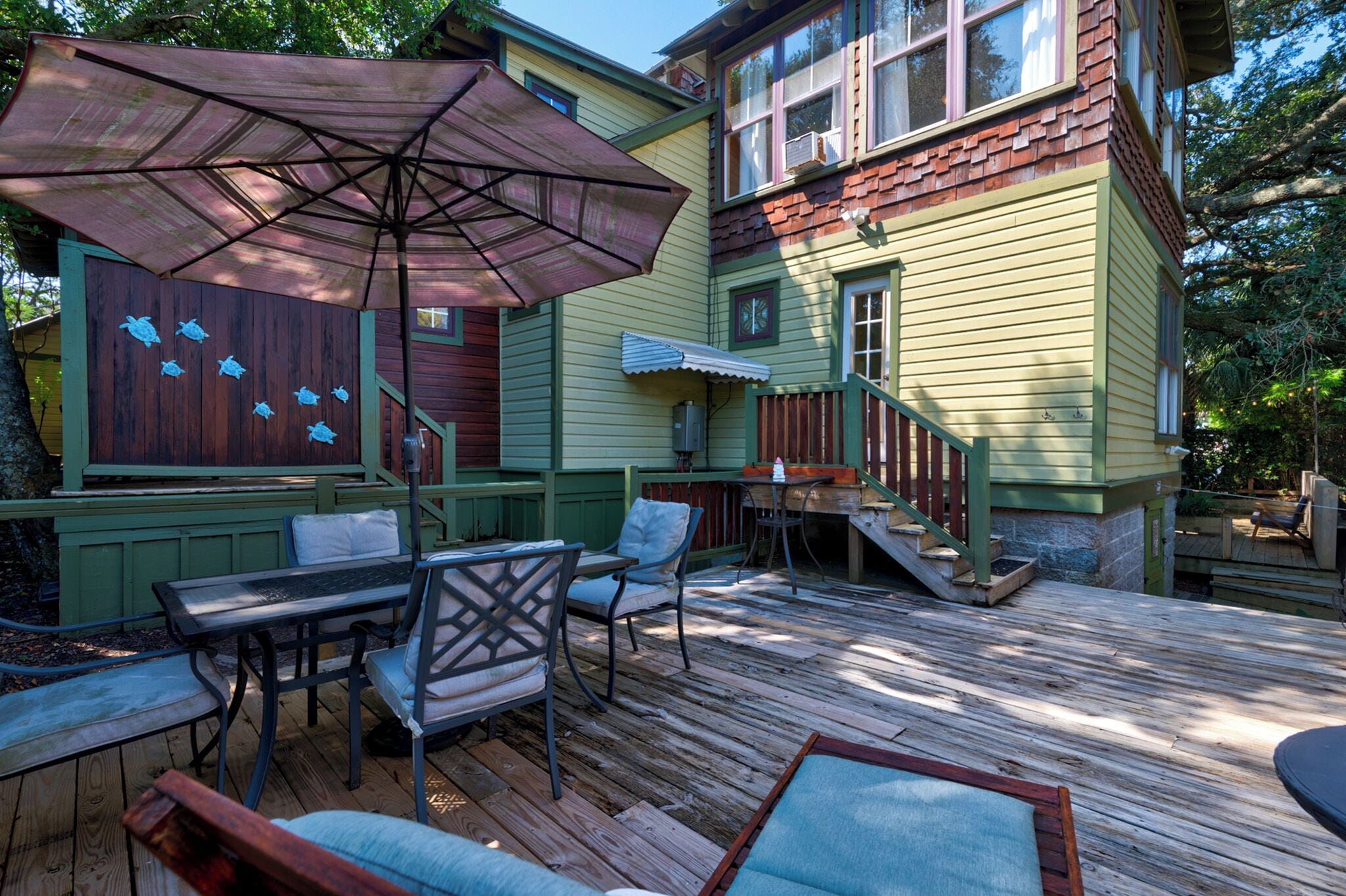 A wooden deck with outdoor furniture, including a table and chairs, and a large umbrella.