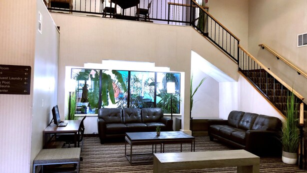 A spacious lobby with a staircase, leather sofas, a coffee table, and a view of the outdoors. - Navajoland Inn (St. Michaels)