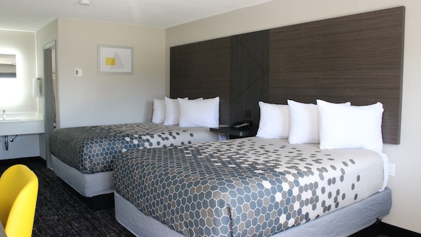 Une chambre d’hôtel avec deux lits, un bureau, une chaise et une grande fenêtre.