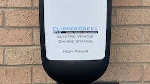Une borne de recharge pour véhicules électriques de la marque ClipperCreek, de couleur blanche et noire, fixée à un mur en briques.