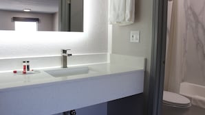 Une salle de bain avec un lavabo blanc, un miroir et des toilettes.