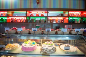A bakery display with various cakes and cookies, each labeled with a price. - Sky Star Hotel (Yangon)