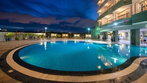 A swimming pool with a tiled edge, surrounded by a building with multiple balconies and a well-lit exterior. - Sky Star Hotel (Yangon)