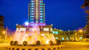 A hotel with a prominent sign, a fountain, and a well-lit entrance. - Sky Star Hotel (Yangon)