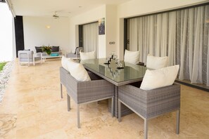A dining area with a glass table, grey wicker chairs, and white cushions. - Aligio Aparthotel & Spa (Las Terrenas)