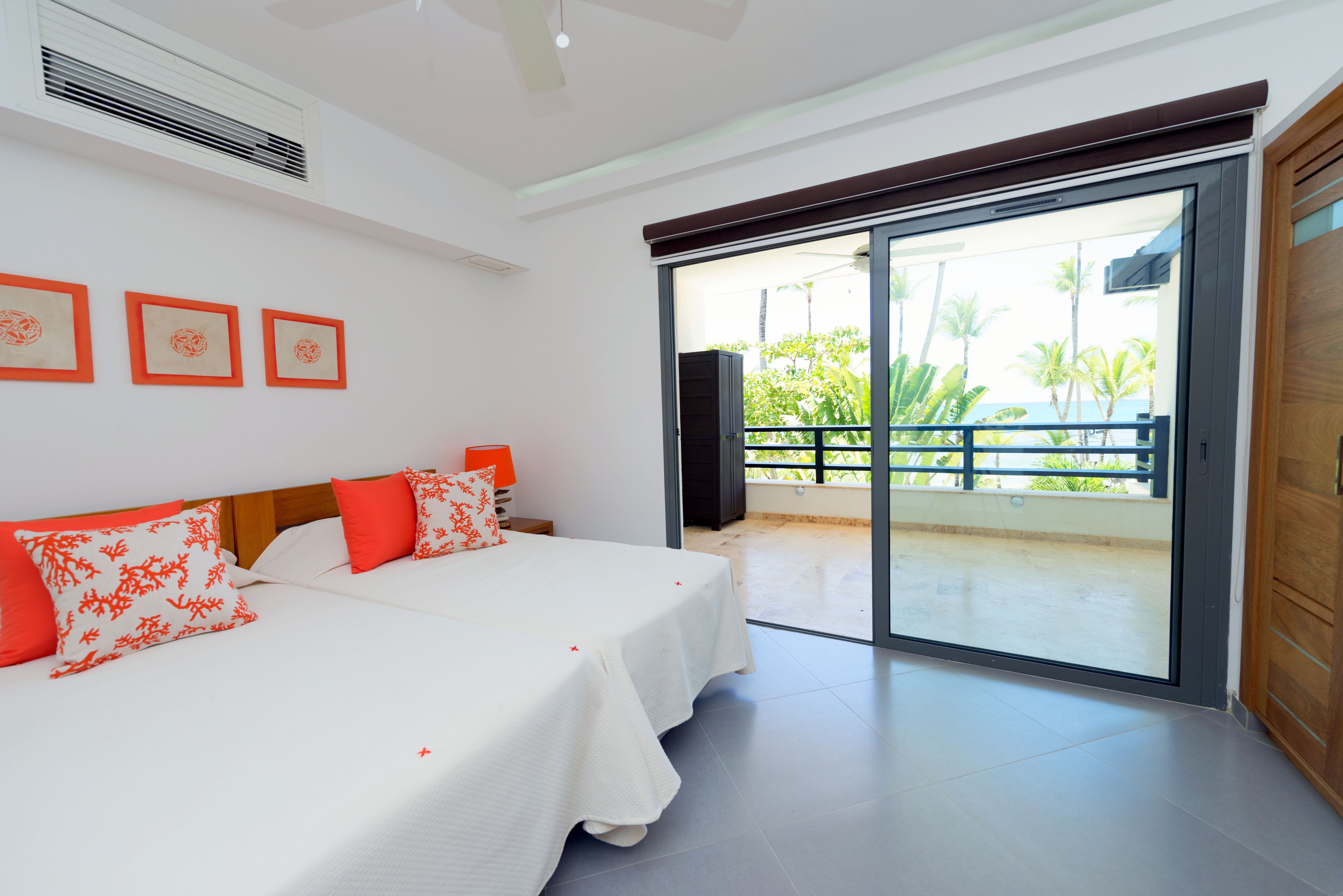 Habitación de hotel con cama, mesita de noche y puerta corrediza de vidrio que da a un balcón.