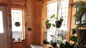 A wooden cabin interior with a bench, potted plants, and a rug. - Twin Peaks Lodge and RV Park (Seward)