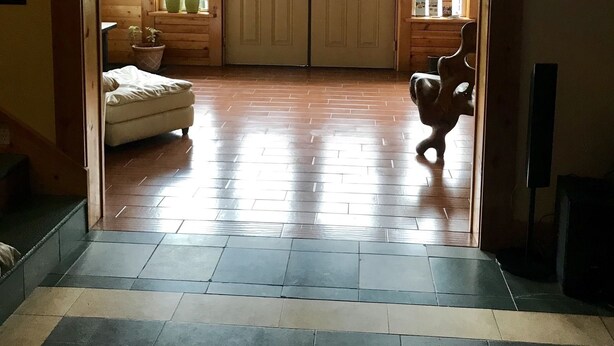 A wooden door with a window, a tiled floor, and a small dog in the doorway. - Twin Peaks Lodge and RV Park (Seward)