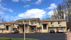 A two-story motel with a parking lot and a small lawn area. - Colonade Motel (Hightstown)