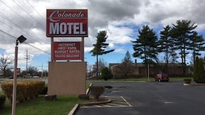 A motel sign with amenities including internet, HBO, ESPN, budget rates, and trucks welcome. - Colonade Motel (Hightstown)