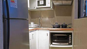 Una cocina compacta con horno integrado, microondas y refrigerador.