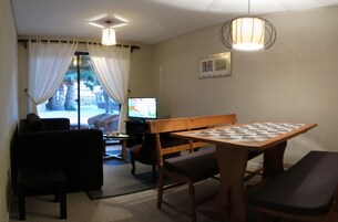 Una habitación acogedora con una mesa y sillas de madera, un televisor y vistas a palmeras.