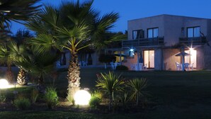 A modern building with a flat roof and large windows, surrounded by a well-maintained garden with palm trees and other plants. - Apart Hotel Gran Pacifico (La Serena)