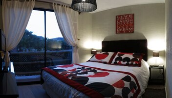 Un dormitorio con una cama grande, vistas a palmeras a través de una ventana y una cita motivacional en la pared.