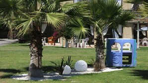 A well-maintained garden with palm trees, a play area with blue and white structures, and a white spherical sculpture. - Apart Hotel Gran Pacifico (La Serena)