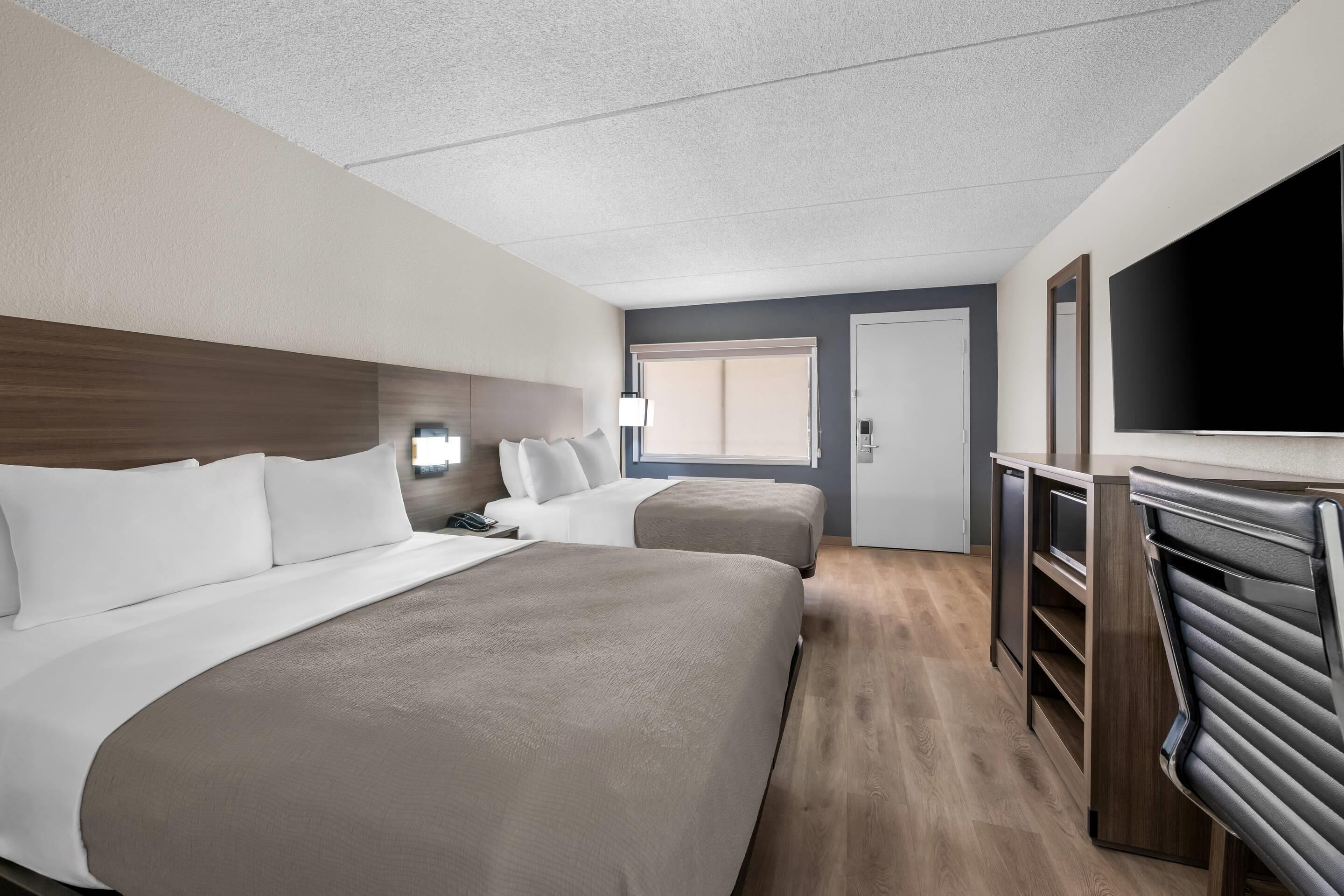 Et hotelværelse med to senge, fjernsyn, skrivebord og et walk-in closet.