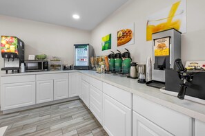 A modern kitchen with a coffee machine, waffle maker, and a refrigerator.