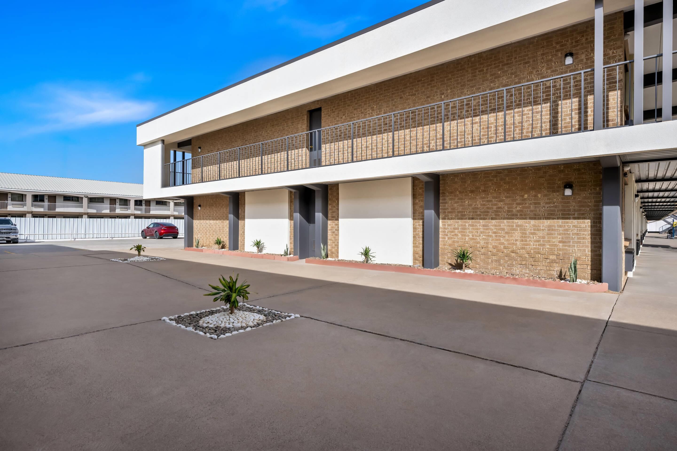 Un hôtel moderne à la structure à deux étages, doté d’un espace extérieur couvert et d’un parking.