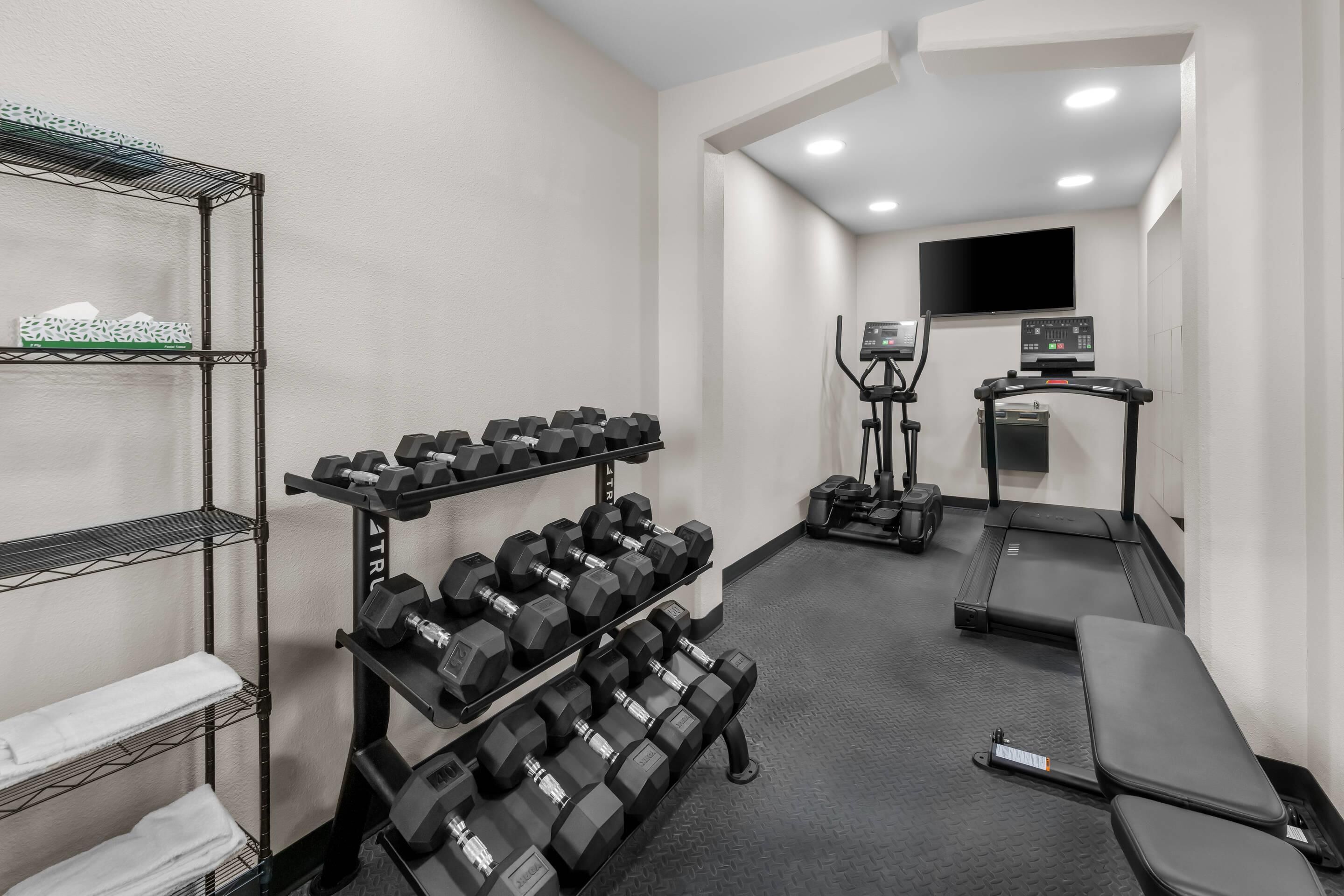 Un gimnasio con mancuernas, una cinta de correr y una pantalla de televisión.