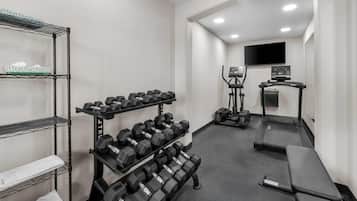 Un gimnasio con mancuernas, una cinta de correr y una pantalla de televisión.