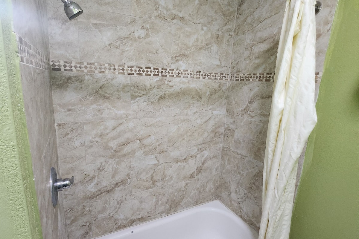 Ein Badezimmer mit einer Badewanne, einer Duschvorhang und einer gefliesten Wand.