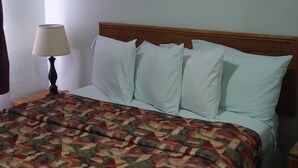 Ein ordentlich bezogenes Bett mit einem gemusterten Überwurf, einem Holzkopfende und einer Nachttischlampe.