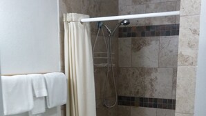 Ein Badezimmer mit Toilette, einer Duschkabine mit Vorhang und gefliesten Wänden.