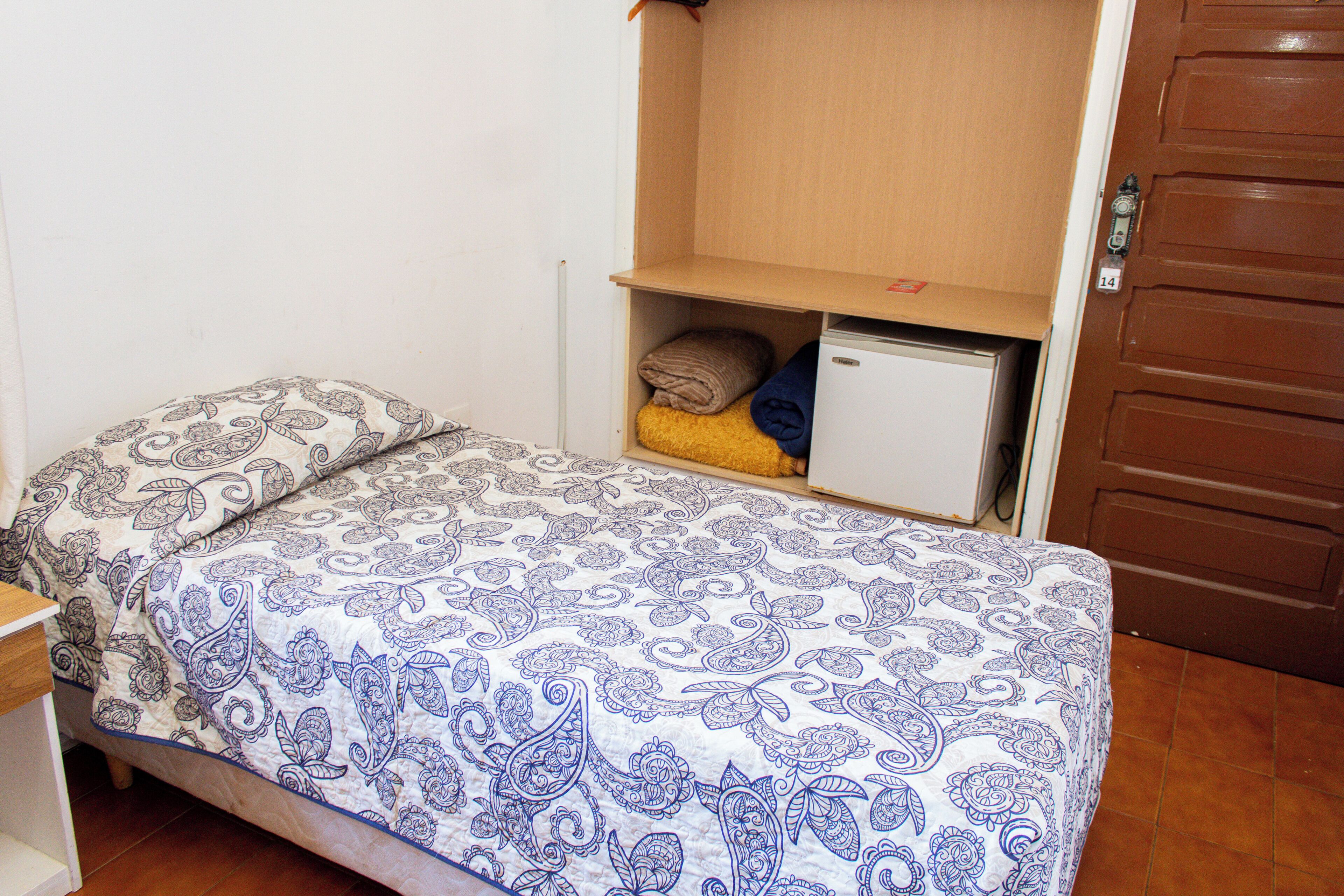 A bedroom with a bed, a nightstand, a wardrobe, and a small cabinet.