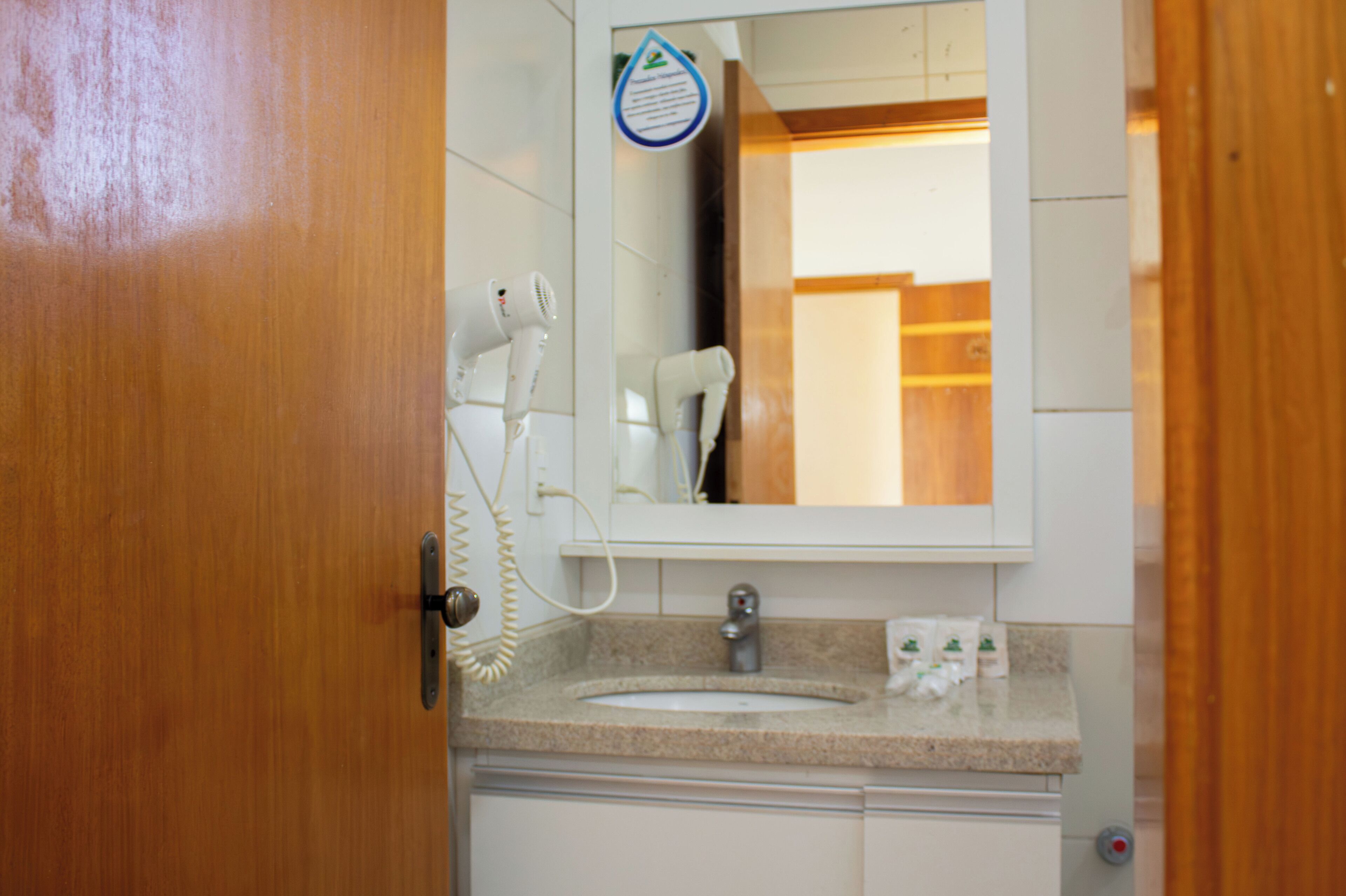 A bathroom with a sink, mirror, and hair dryers.