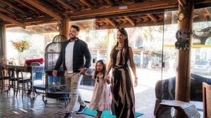 A family walking through a rustic interior with wooden beams, a birdcage, and a wooden stool. - Hotel Fazenda Pocos de Caldas (Poços de Caldas)