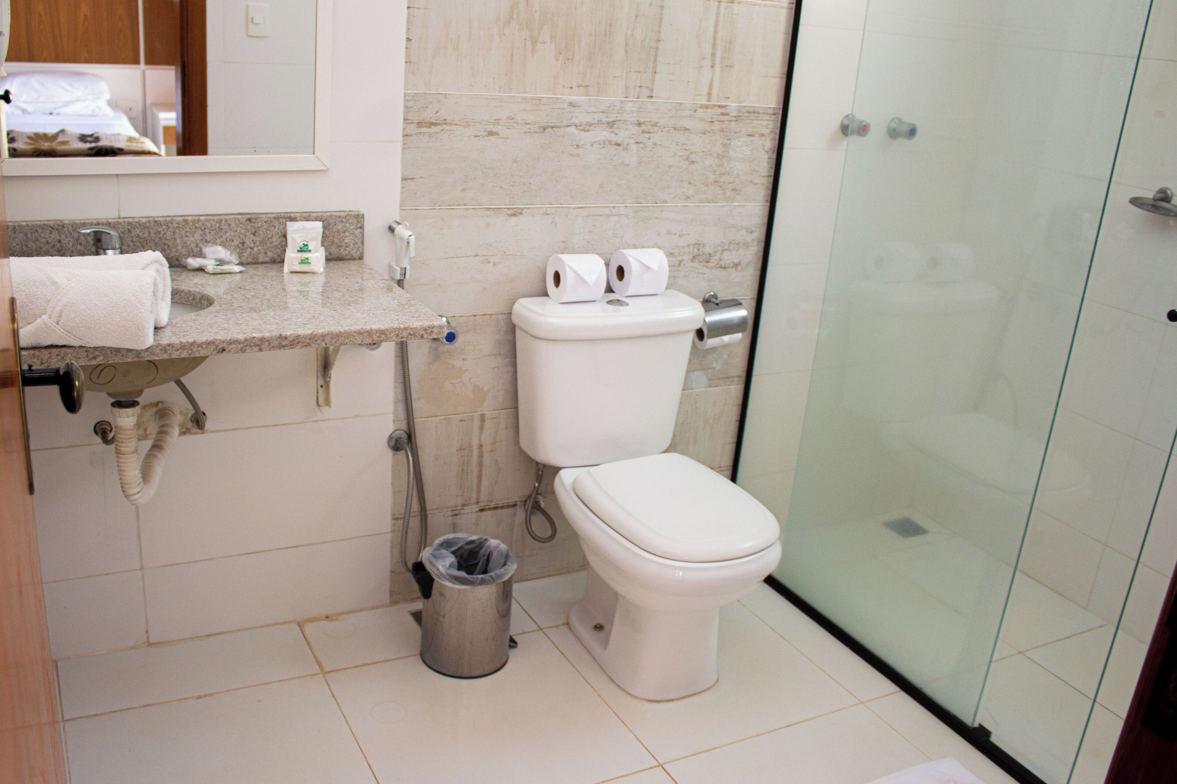 Un baño moderno con inodoro, lavamanos y ducha envuelta en vidrio.