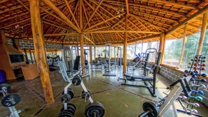 A gym with wooden beams, exercise equipment, and a brick wall. - Hotel Fazenda Pocos de Caldas (Poços de Caldas)