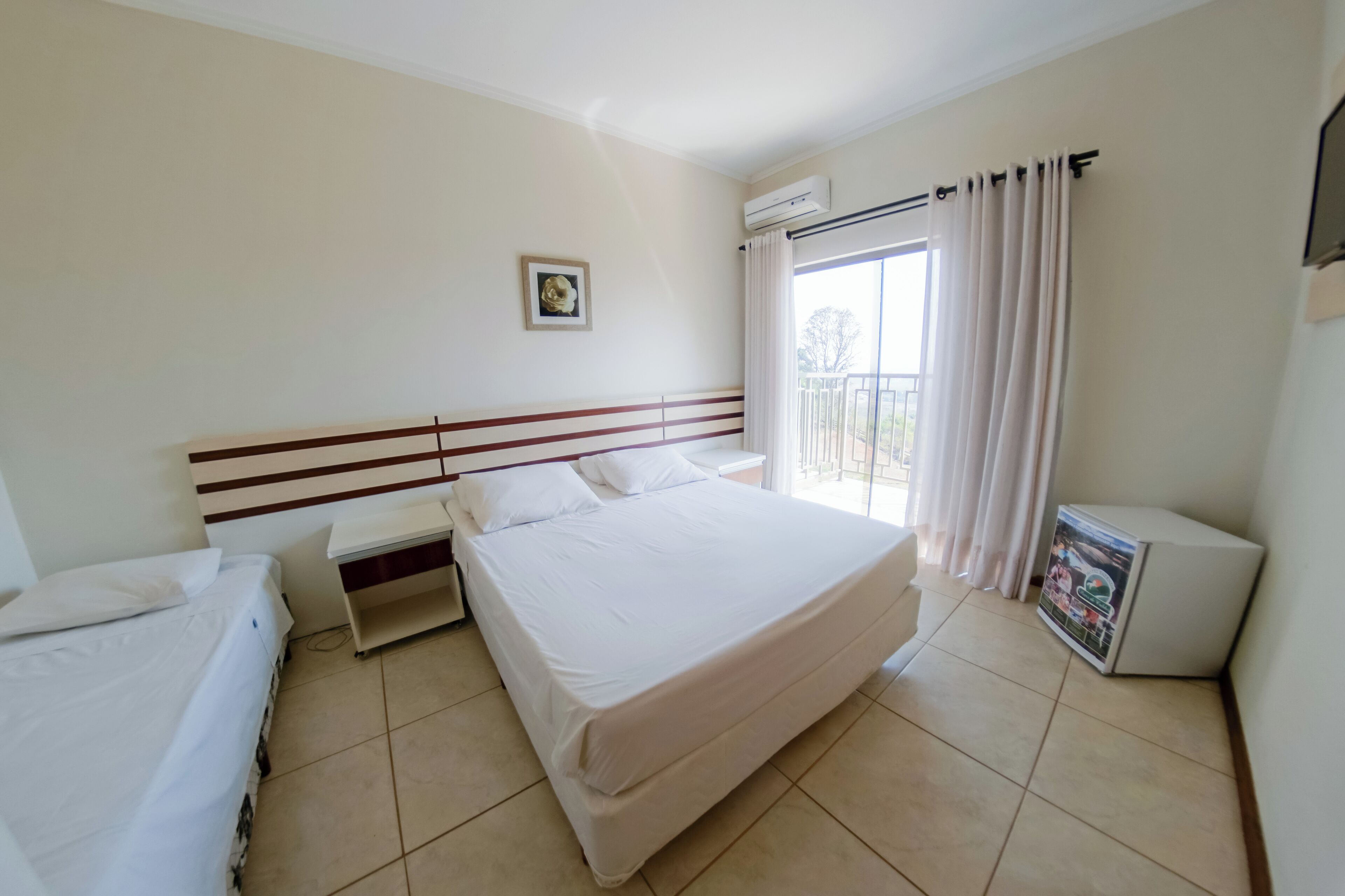 A hotel room with a large bed, a smaller bed, a desk, and a window with curtains.