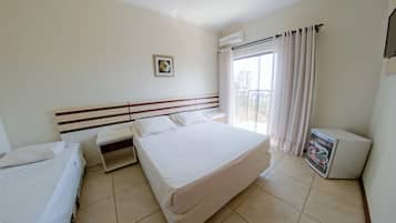 A hotel room with a large bed, a smaller bed, a desk, and a window with curtains.
