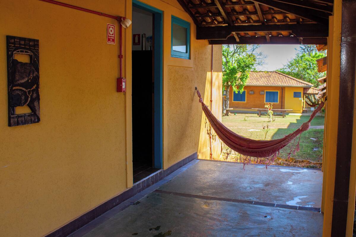 A yellow building with a hammock hanging in front of an open doorway.