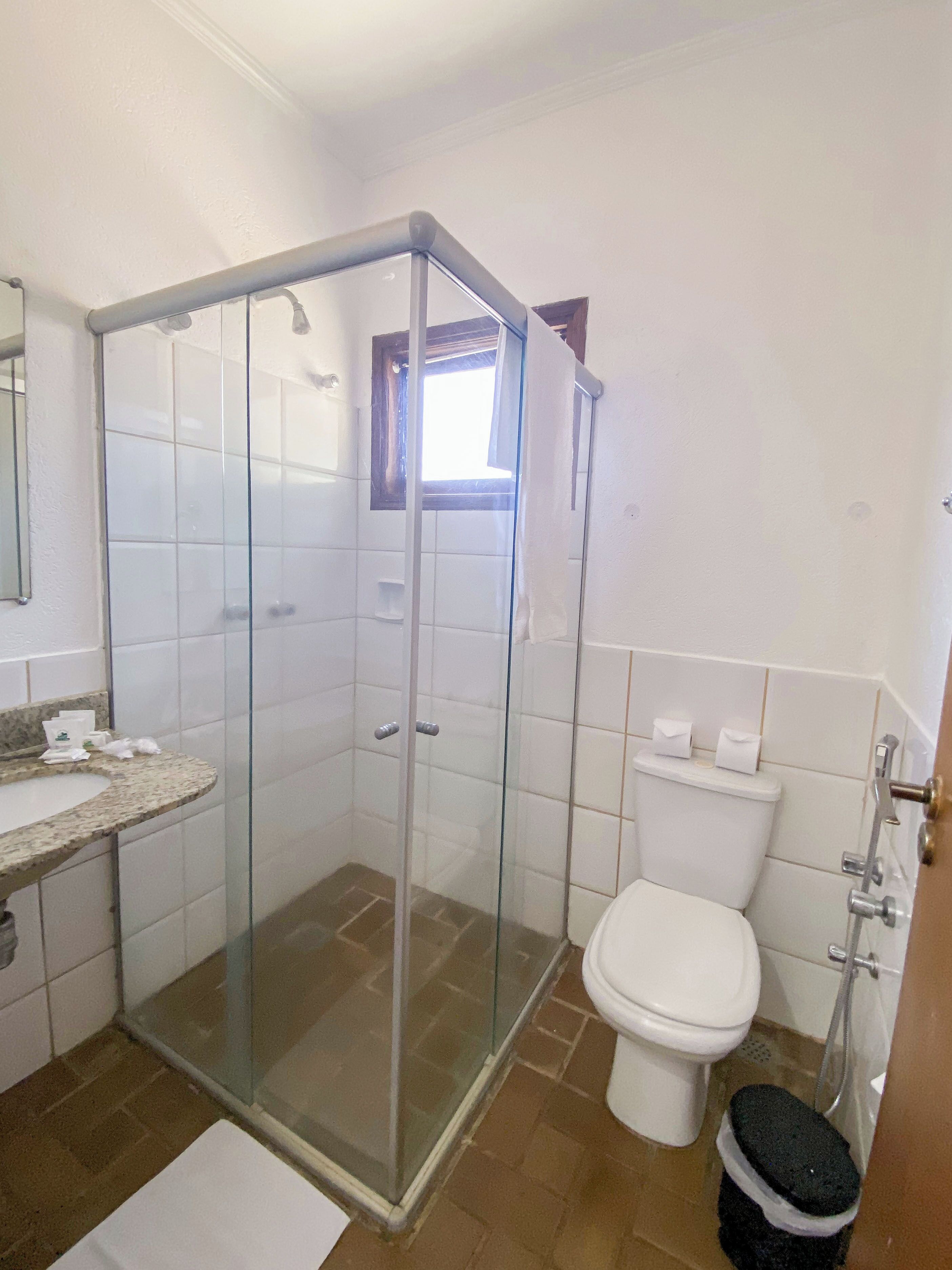 A bathroom with a glass-enclosed shower, a toilet, and a sink.