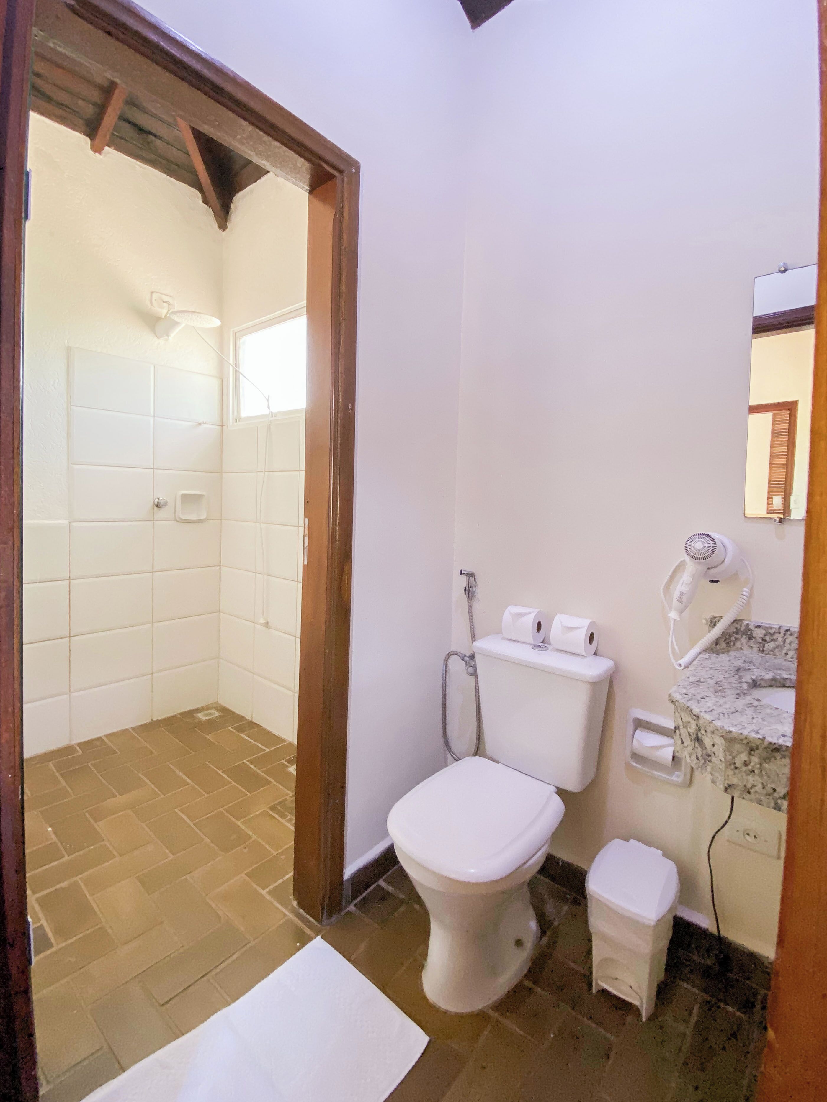 A bathroom with a toilet, a shower, and a sink with a mirror.
