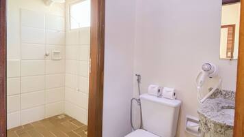 A bathroom with a toilet, a shower, and a sink with a mirror.