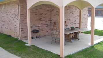 Un patio couvert avec un mur en briques, une table en bois et une chaise.