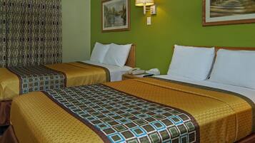 Ein Hotelzimmer mit zwei Betten, grünen Wänden, gemusterten Vorhängen und einem Gemälde.