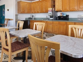 Una cocina pequeña con armarios de madera, una cafetera y un comedor con sillas de madera y una mesa de mármol.