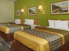 Habitación de hotel con dos camas, paredes verdes y tres cuadros.
