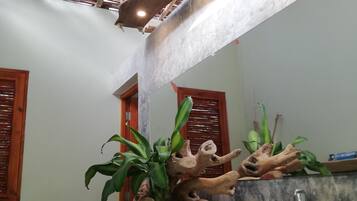 Un baño con techo de madera, lavamanos de mármol y arreglos de plantas.