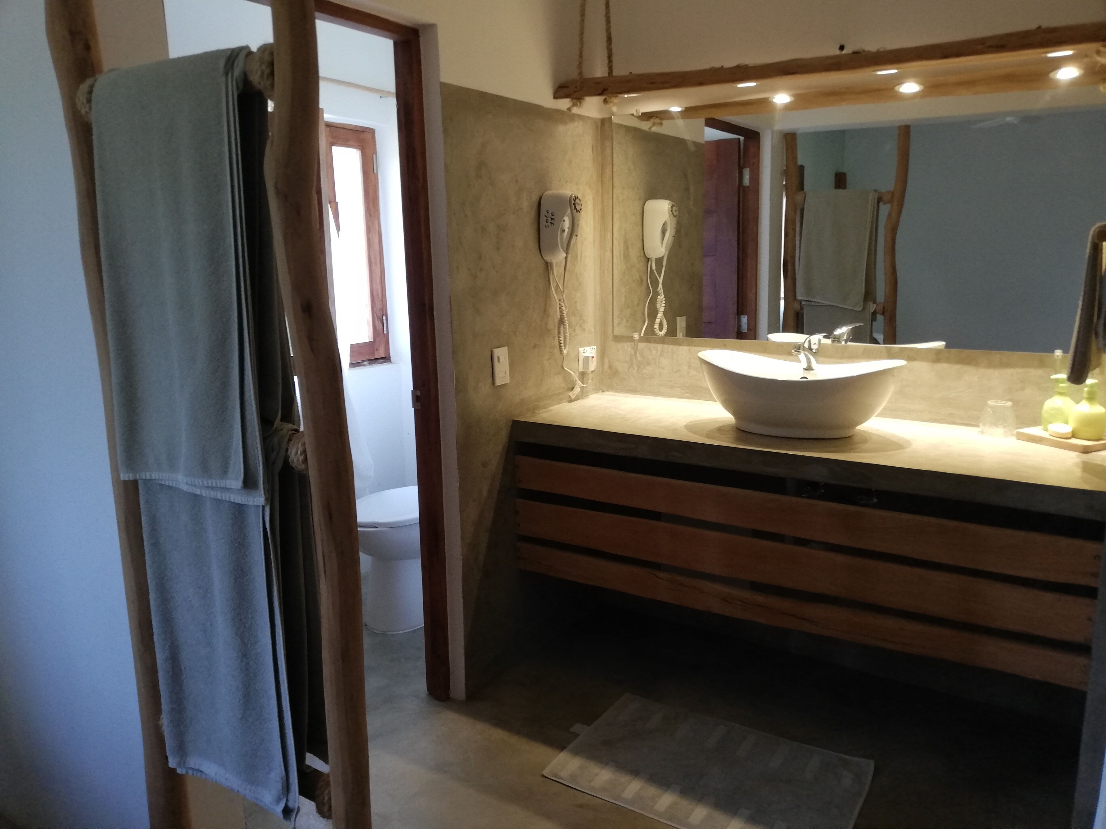 A bathroom with a large sink, a mirror, and a towel rack.