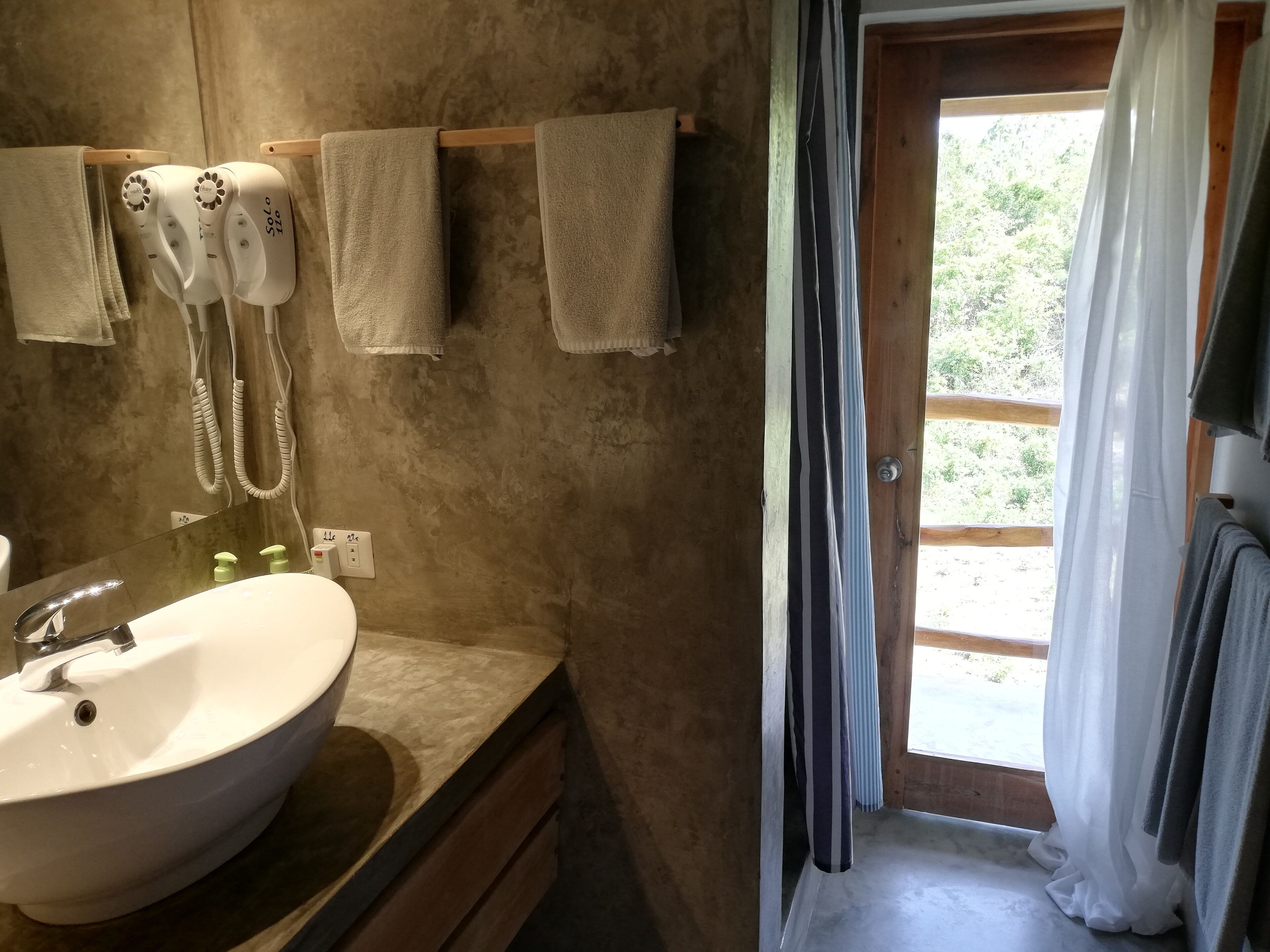 A bathroom with a sink, towel rack, and a view of the outdoors through a door.