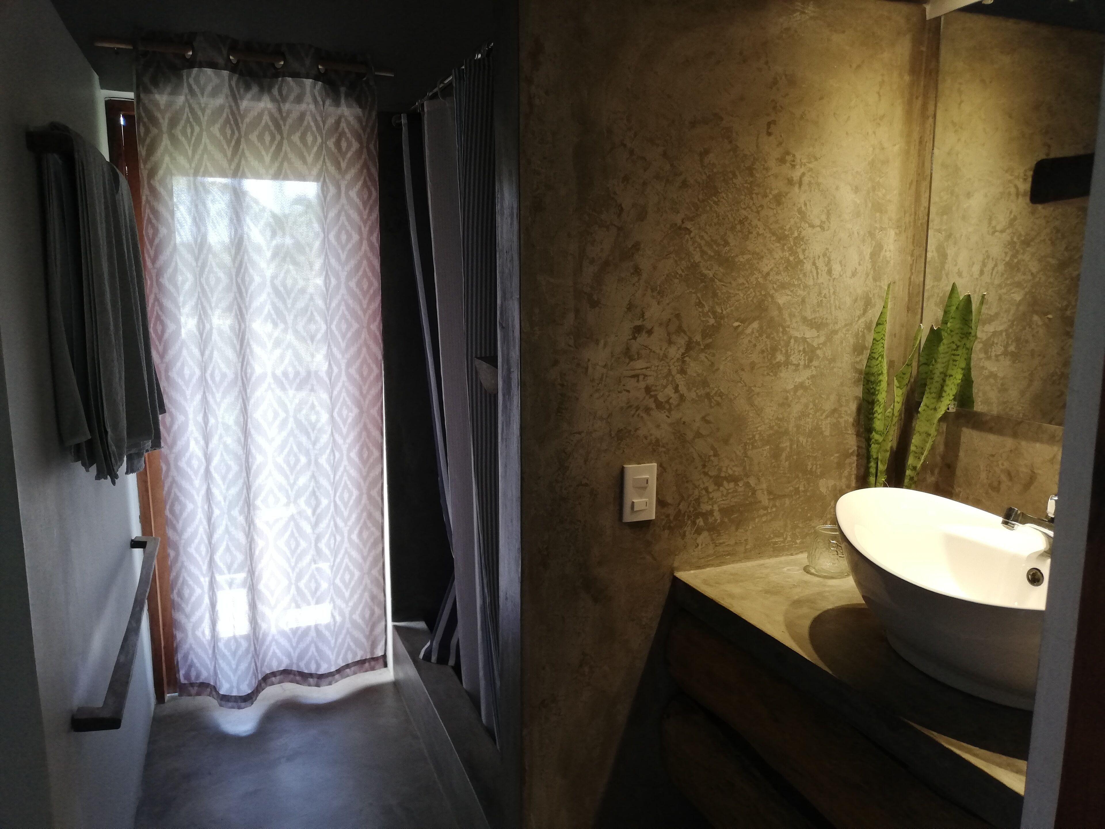 Une salle de bain avec un grand lavabo, un miroir et un rideau de douche à motifs.